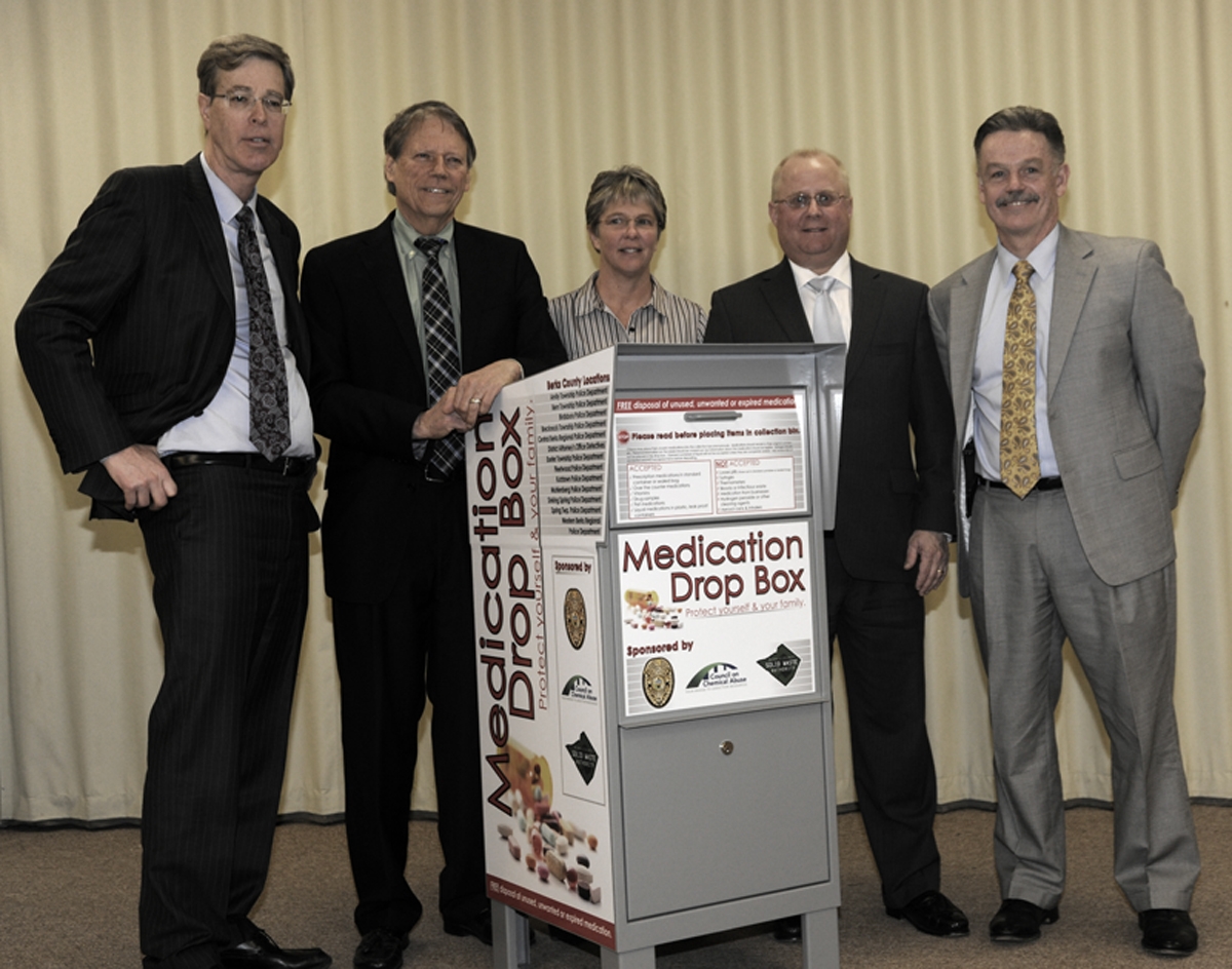 People standing behind a medicaiton drop box